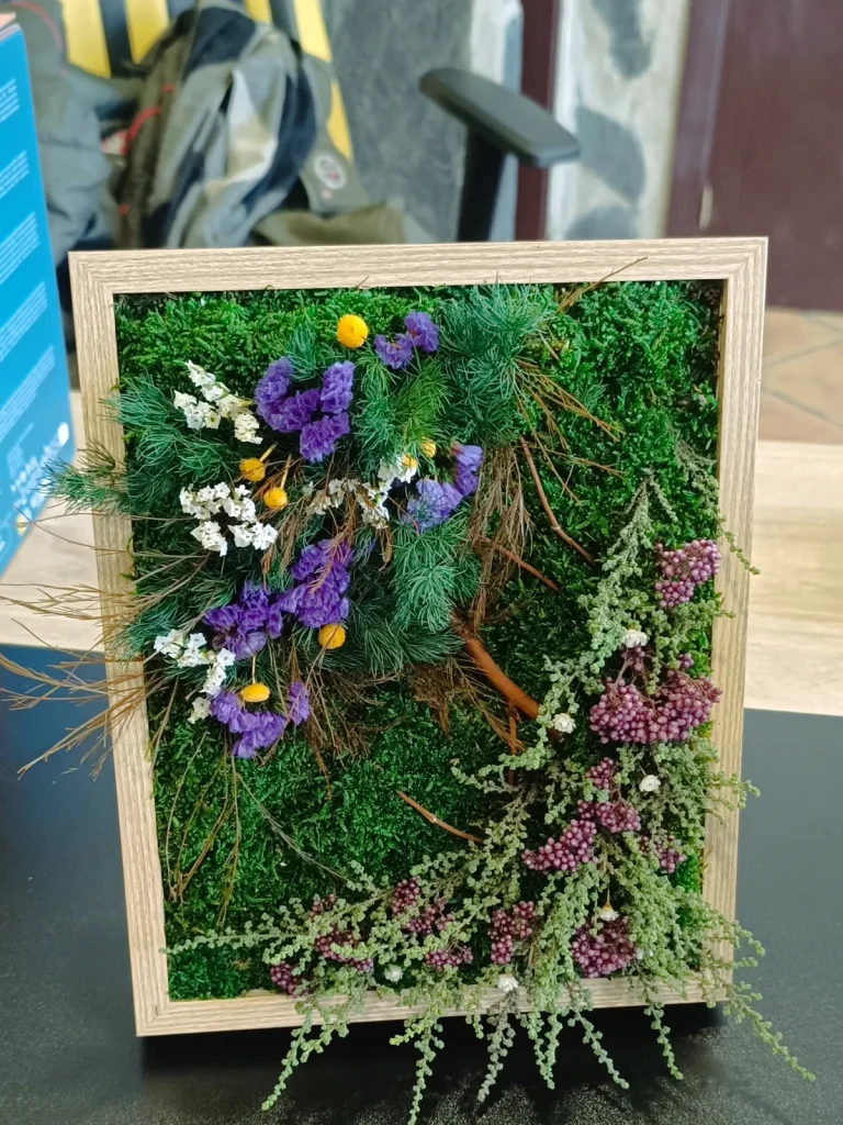 Cuadro de musgo preservado con flores secas moradas y marco de madera clara